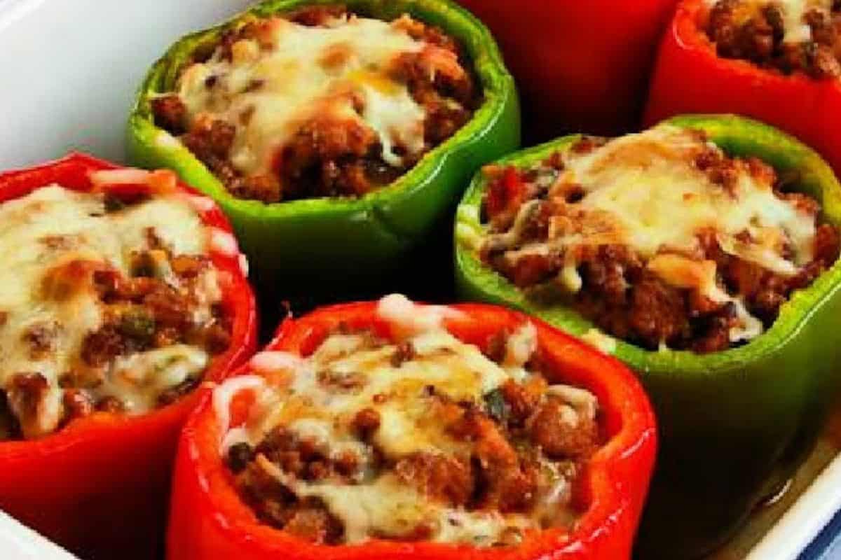 Easy stuffed peppers—red and green, filled with savory ground meat and topped with melted cheese—make the perfect weeknight dinner, all arranged in a white baking dish.
