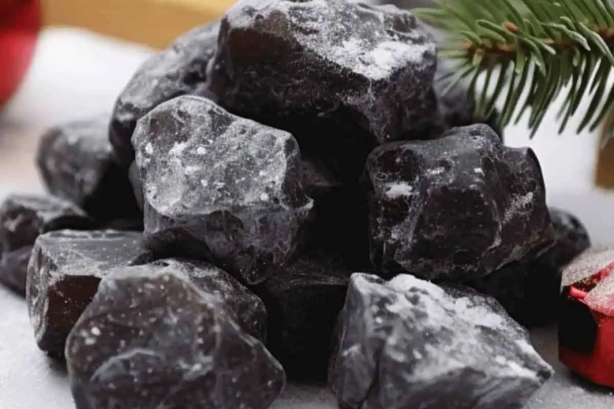 Lumpy black candy pieces resembling coal, arranged on a white plate.