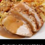 Sliced turkey breast with turkey gravy from the drippings, served with stuffing and scalloped potatoes on a white plate; garnished with parsley.