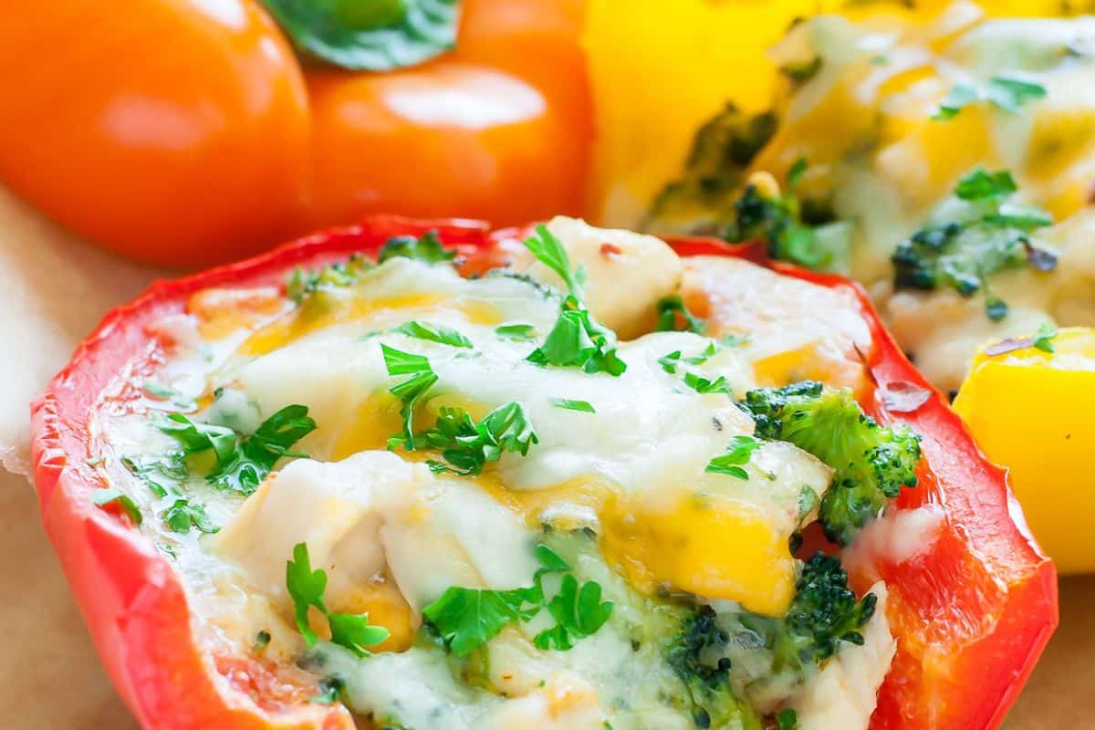 Close-up of a stuffed bell pepper filled with vegetables, topped with melted cheese and chopped parsley—perfect for easy stuffed peppers and delicious weeknight dinners. Other bell peppers appear in the background.