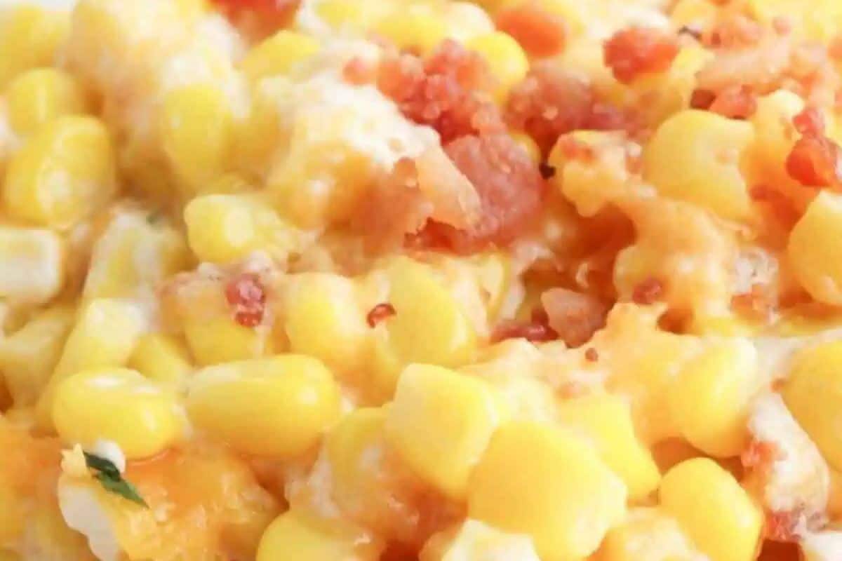 Close-up of a dish featuring yellow corn kernels mixed with melted cheese and sprinkled with small pieces of bacon—an unbelievably good choice for cooler weather and a must-try among casserole recipes.