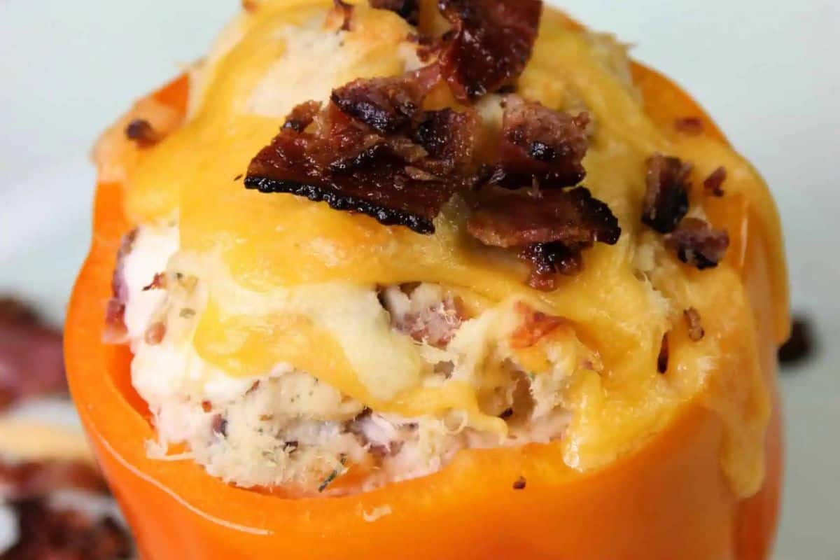 A close-up of an orange bell pepper stuffed with a creamy filling, topped with melted cheese and crispy bacon bits—perfect inspiration for easy stuffed pepper recipes and quick weeknight dinners.