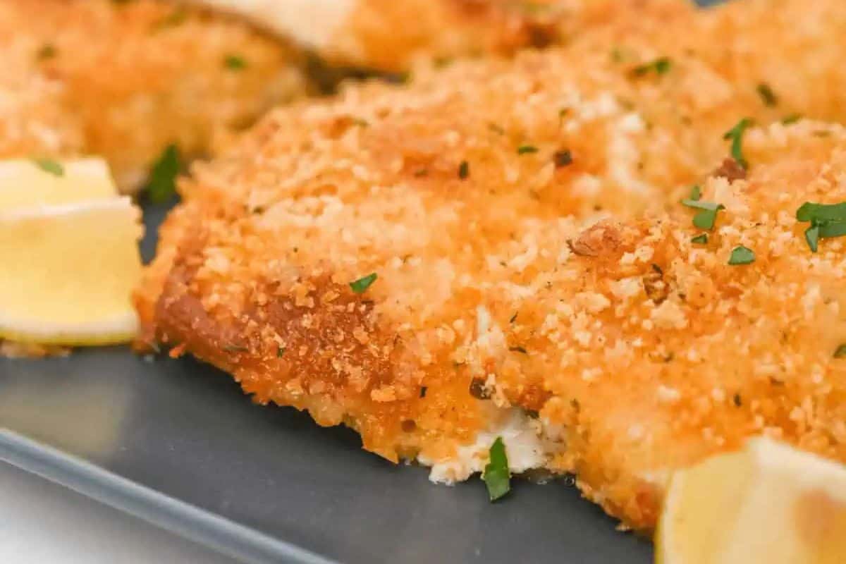 Close-up of parmesan herb crusted chicken on a baking sheet.