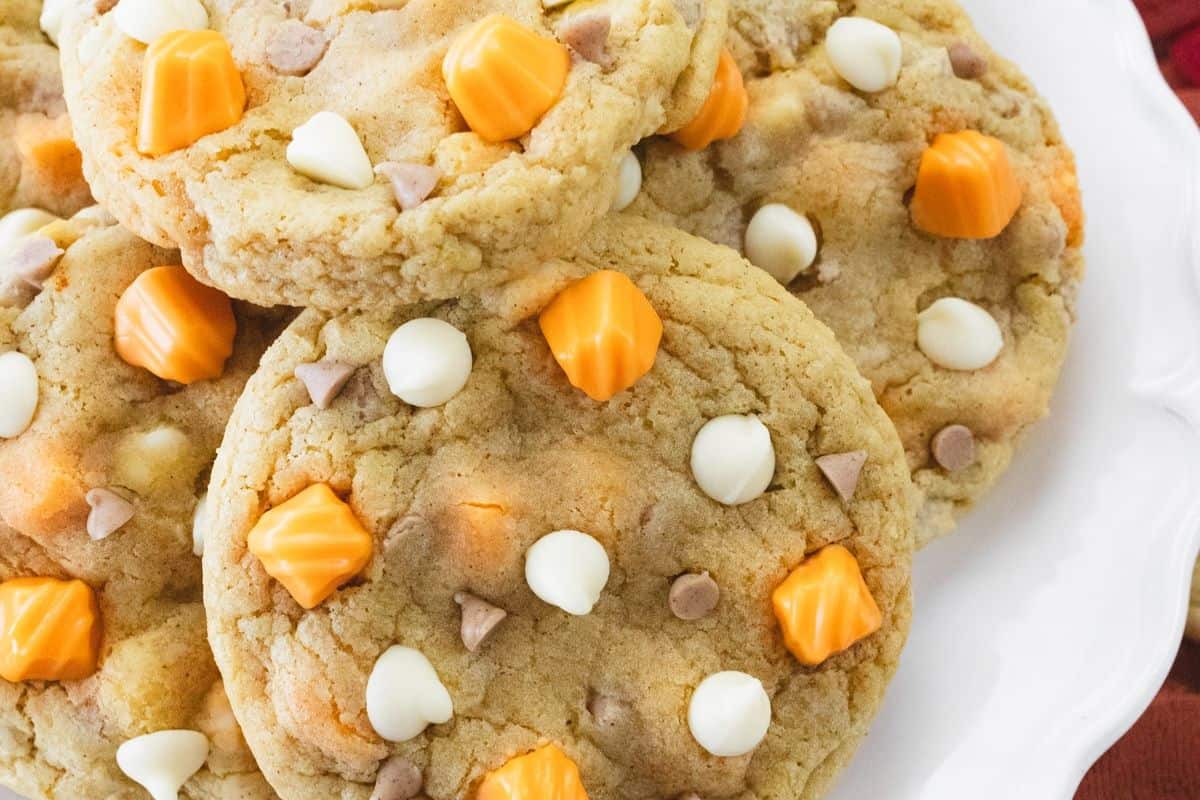 A plate of cookies topped with white and orange candy melts and small chocolate chips, perfect for cozy fall vibes and a delightful addition to your favorite fall desserts.