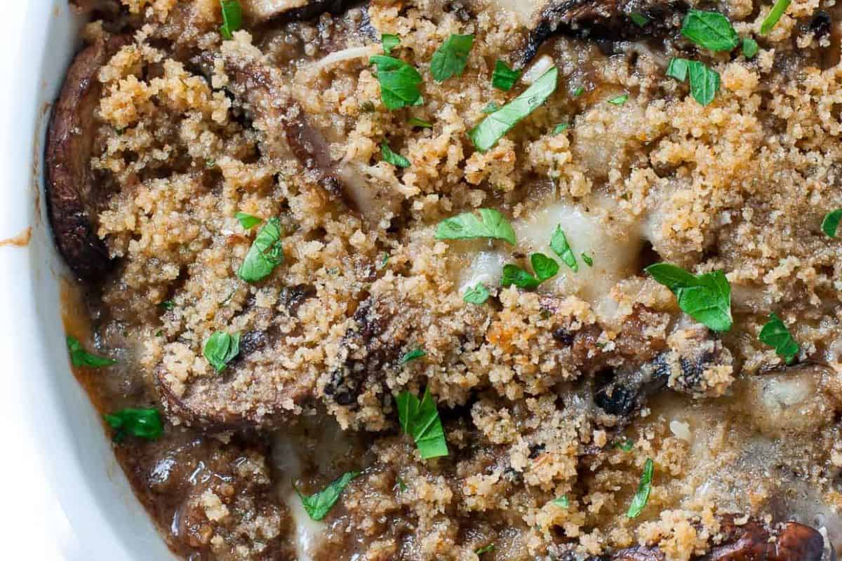 Close-up of a baked mushroom casserole topped with golden breadcrumbs and garnished with chopped fresh herbs—perfect for cooler weather and those who love comforting casserole recipes.