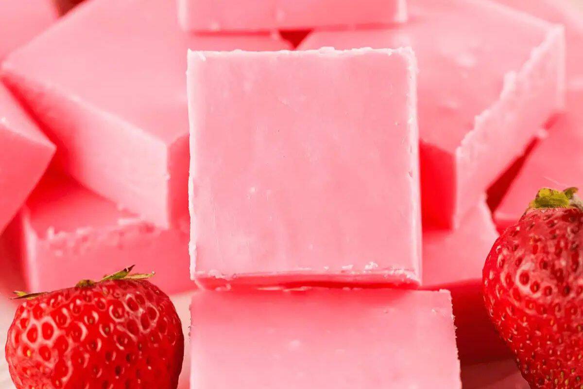 Creative Valentine fudge squares, bursting with strawberry flavor, are perfectly stacked with two fresh strawberries in the foreground—ideal for those Little Sweethearts celebrating love.