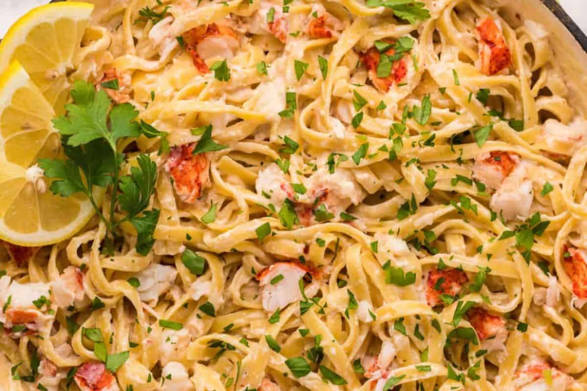 Close-up of creamy pasta garnished with chopped parsley, lemon slices, and herb sprigs—perfect for special dinners or cozy nights.