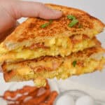 A hand holds a towering breakfast sandwich.