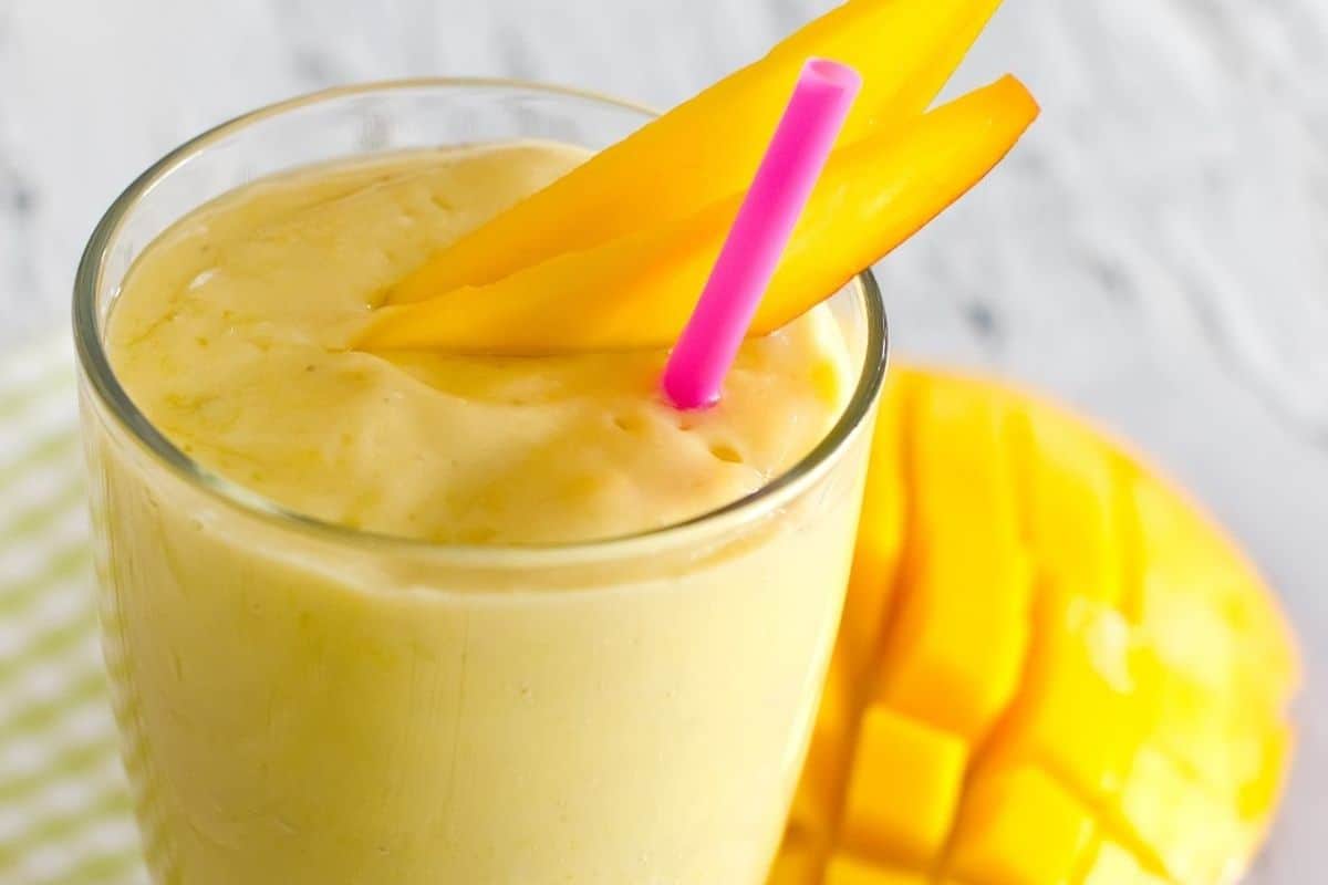 A bahama mama smoothie topped off with two slices of mango.