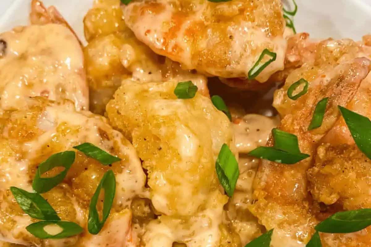 Close-up of crispy bang bang shrimp coated in creamy sauce, garnished with sliced green onions, a perfect addition to your game day party spread. Whether you're hunting for touchdown treats or exploring football-themed recipes, this dish scores big on flavor and presentation.