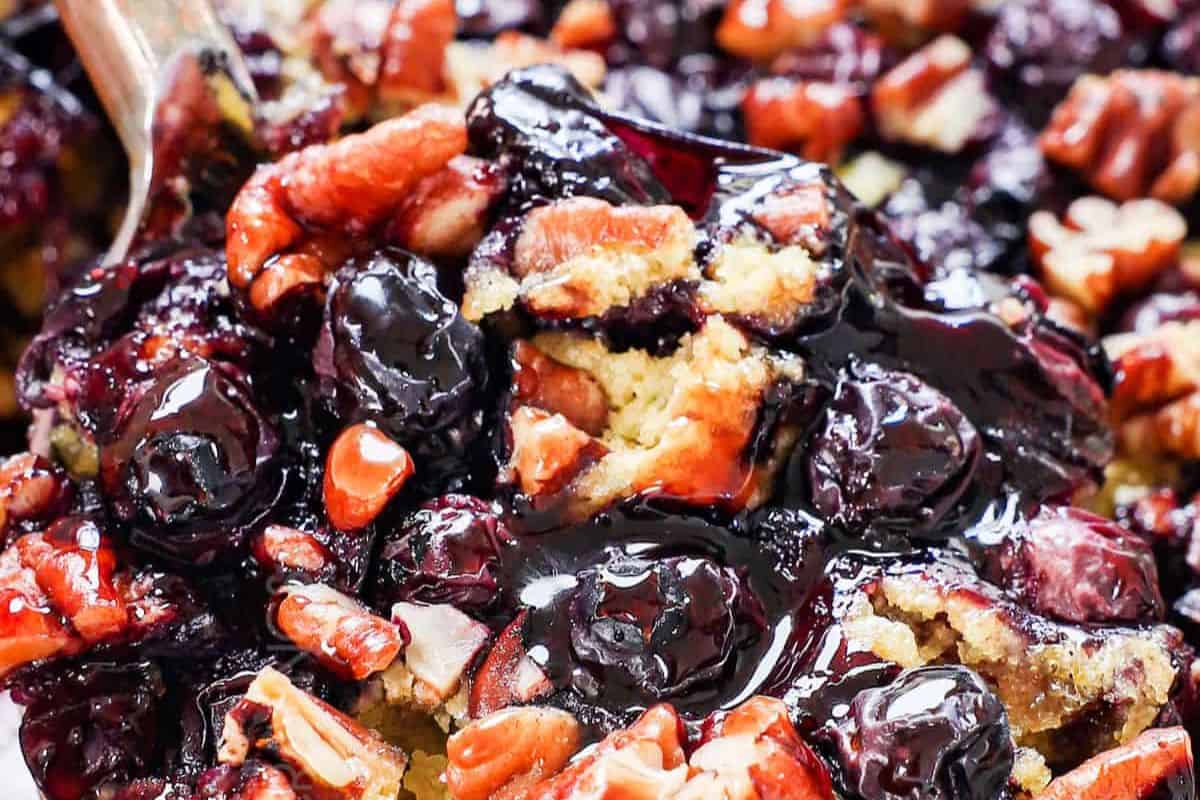 Close-up of some blueberry dump cake, ready to be served with a wooden spoon.