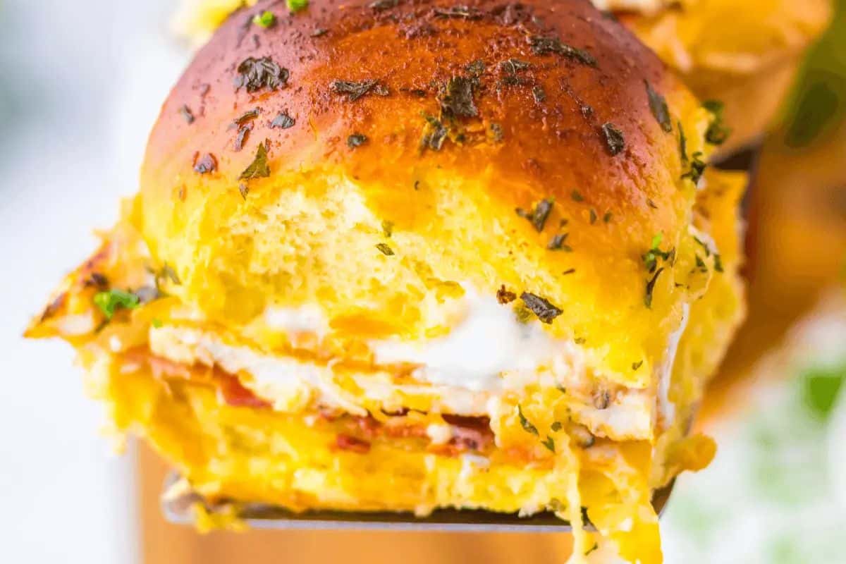 Close-up of an irresistible chicken bacon ranch slider featuring a glossy bun, layers of chicken, ranch, and herbs, with a slice of bacon peeking through—a perfect game day treat.