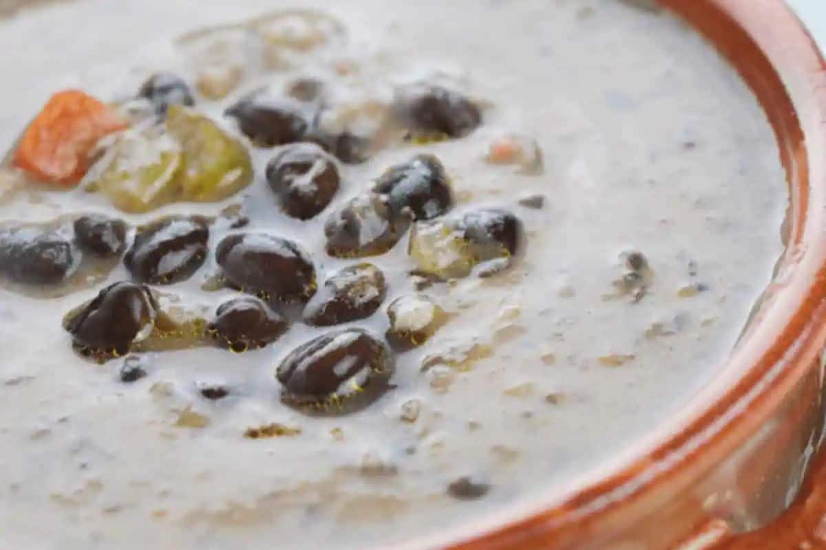 Close-up of a bowl of creamy black bean soup with visible beans and pieces of vegetables, perfect for those who love cozy vegetable soups.