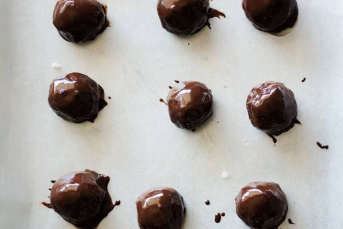Nine round chocolate-coated treats are arranged in rows on a sheet of parchment paper, tempting you to indulge in the ultimate collection of chocolate recipes.