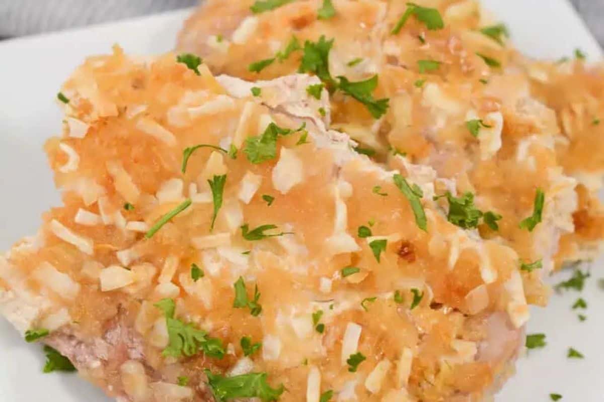 Close-up of some french onion pork chops, served on a white plate.