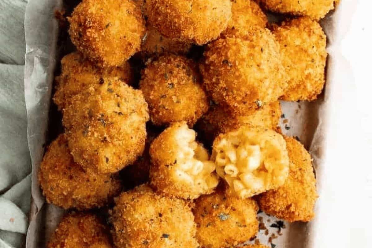 A tray of golden-brown, breaded macaroni and cheese balls, with one ball broken open to reveal the creamy pasta filling inside—perfect for Kid Friendly Dinner Recipes.