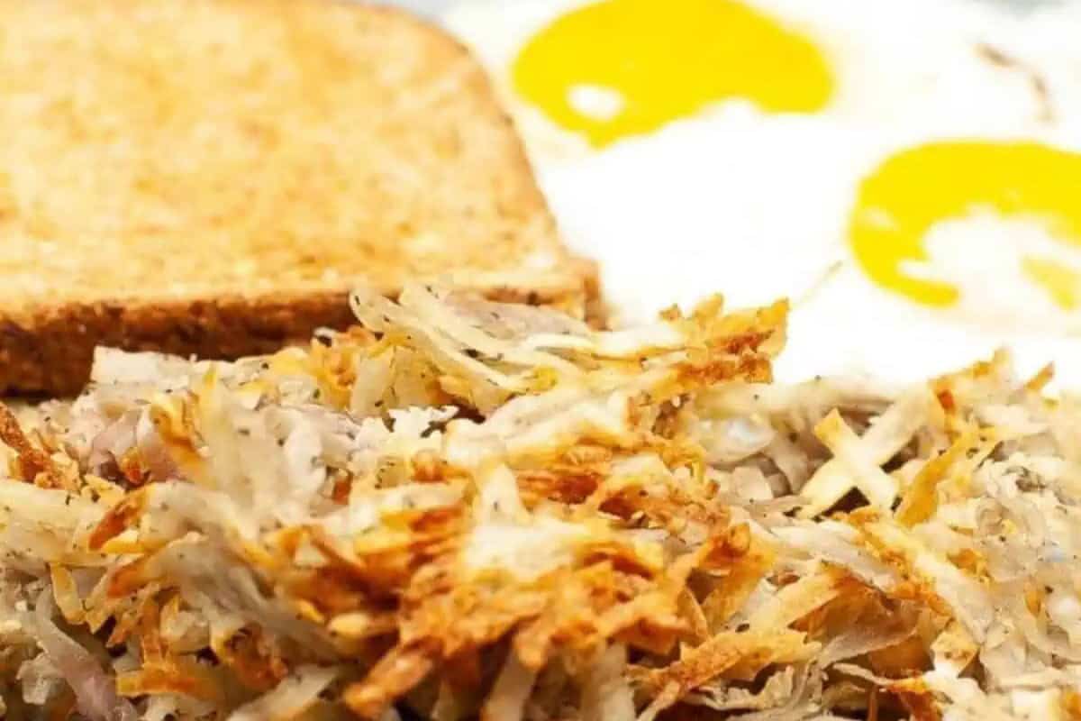 A close-up of hash browns, a slice of toasted bread, and two sunny-side-up eggs on a plate—perfect for easy lazy morning recipes or your next weekend brunch.