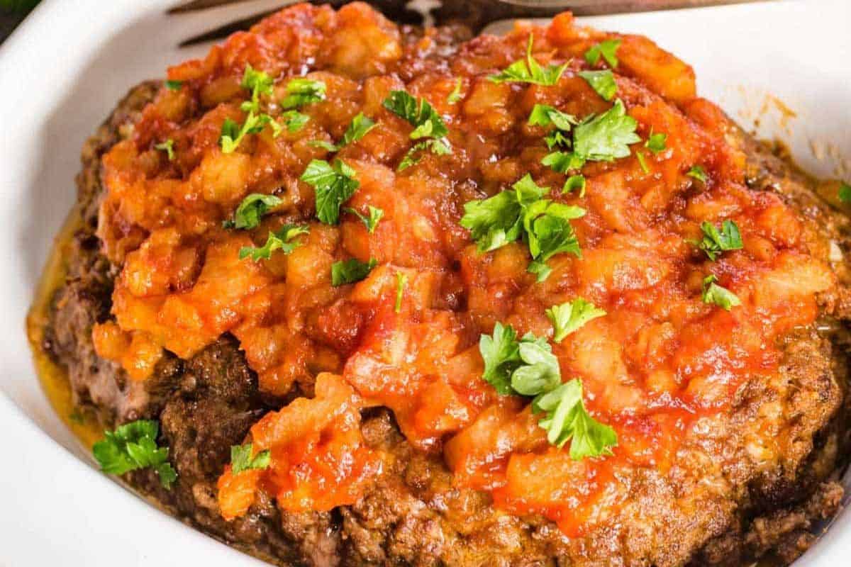 Meatloaf slices topped with pineapple glaze, served in a white baking dish.