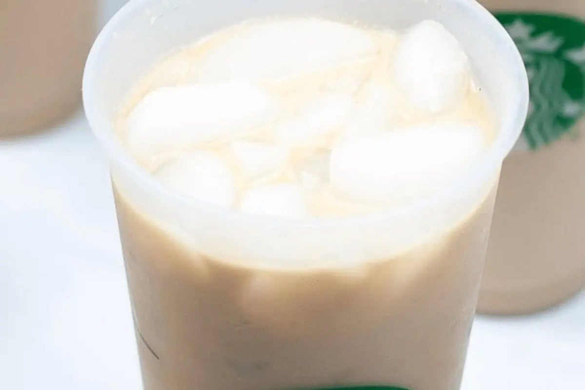 A plastic cup filled with iced coffee and ice cubes, featuring a partially visible green Starbucks logo—perfect inspiration to recreate at home using your favorite Starbucks recipes.