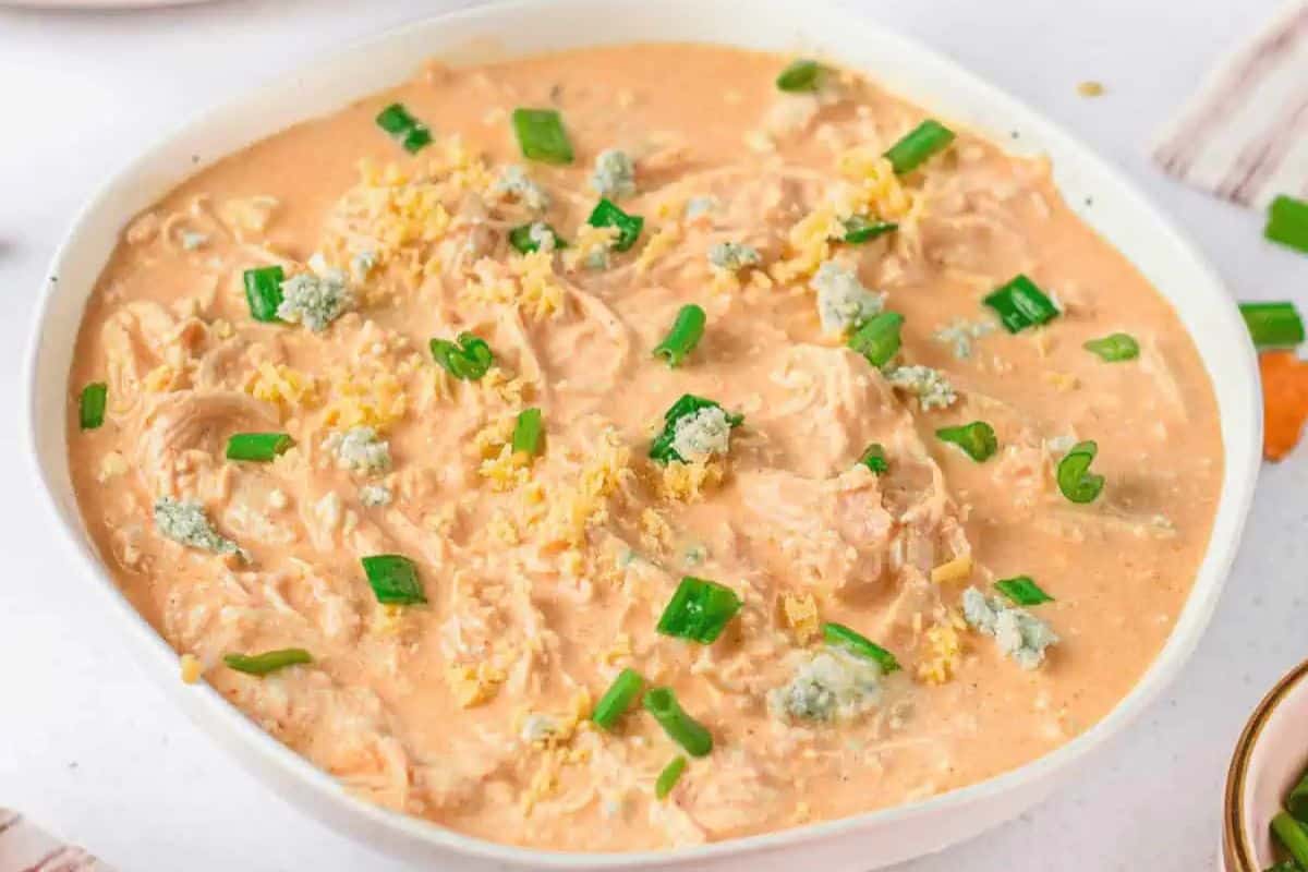 A bowl of creamy buffalo chicken dip topped with crumbled blue cheese, grated cheese, and chopped green onions is sure to score big points at your Super Bowl party.