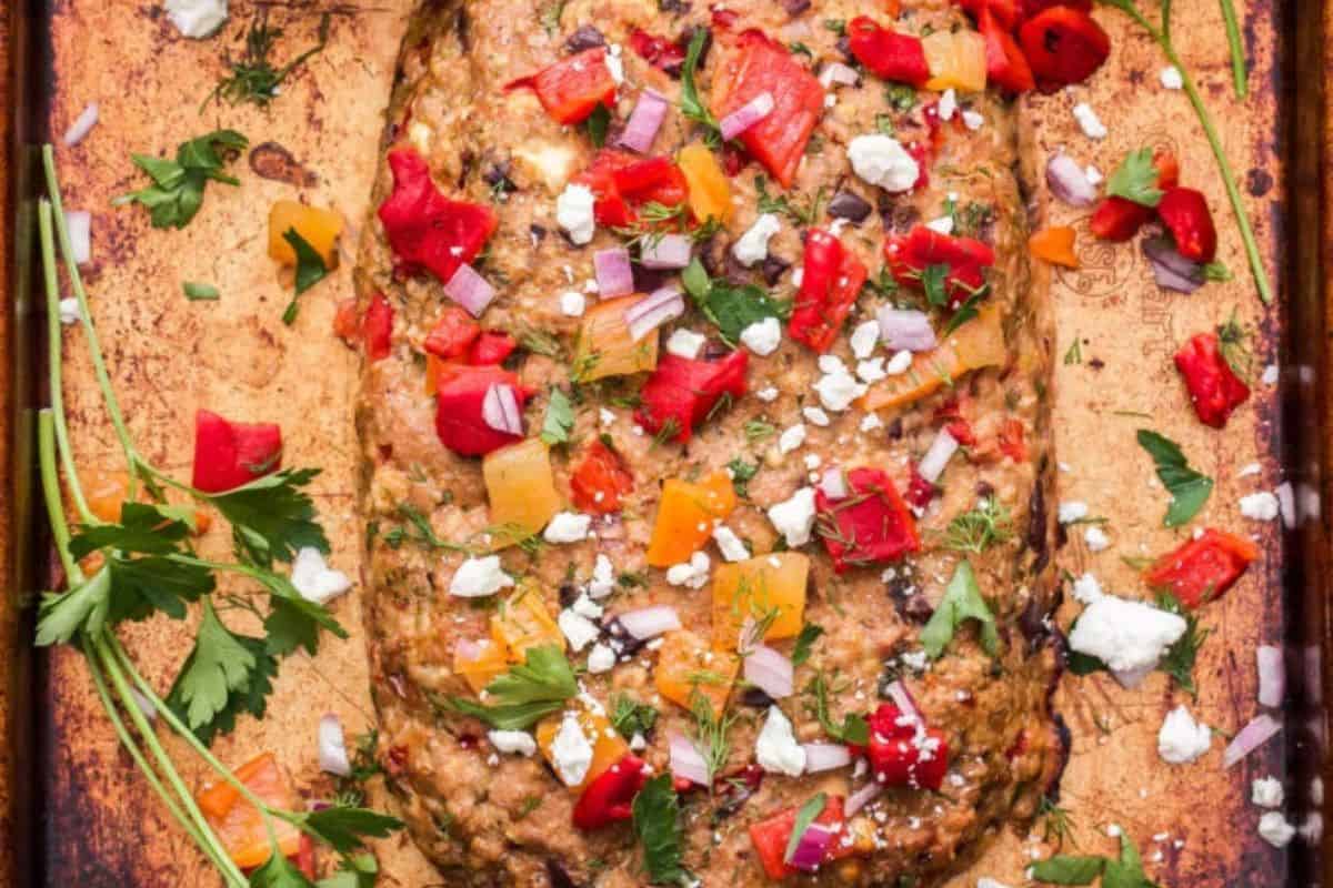 Turkey meatloaf loaf sliced to reveal herbs, sun-dried tomatoes, and feta.