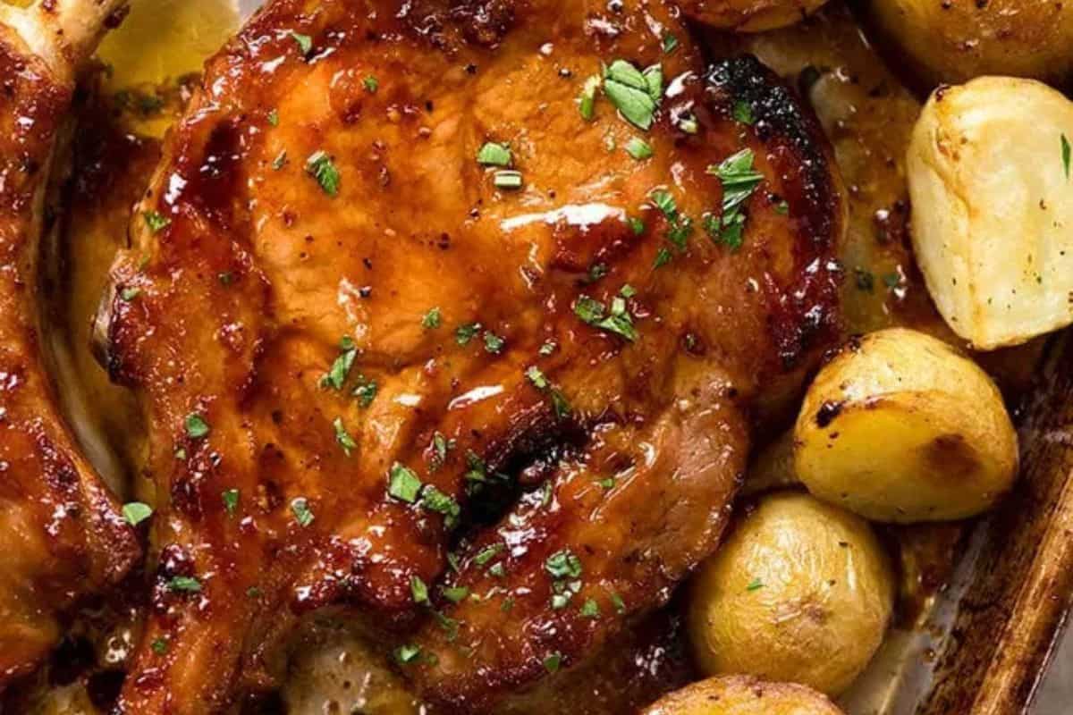 Close-up of some juicy oven baked pork chops, served with some potatoes.