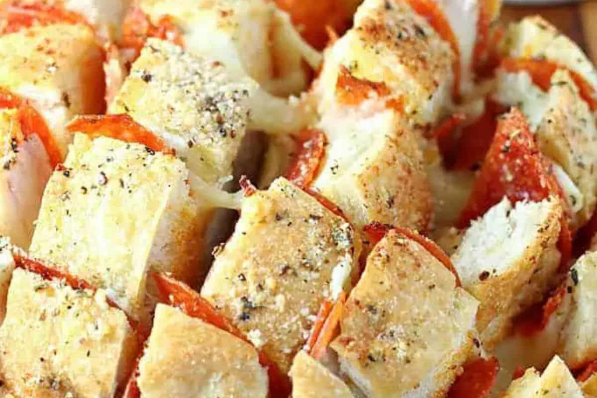 Close-up of sliced pull-apart bread with pepperoni and melted cheese, topped with herbs and seasonings—a perfect Game Day Party snack.