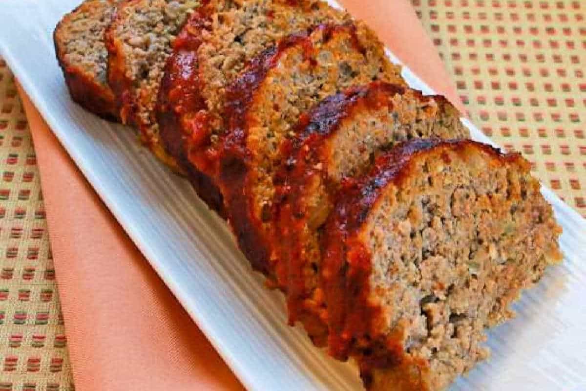 Turkey meatloaf infused with green pesto, sliced and served on a white serving tray.