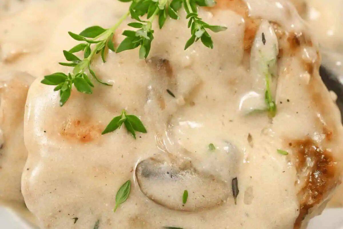 Close-up of a pork chop smothered in a creamy mushroom gravy.