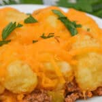A plate of dish topped with mashed potato balls, melted cheddar cheese.