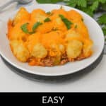 A plate of Sloppy Joe Tater Tot Casserole topped with melted cheese and a sprinkle of fresh parsley. The bottom of the image reads "Easy Sloppy Joe Tater Tot Casserole.