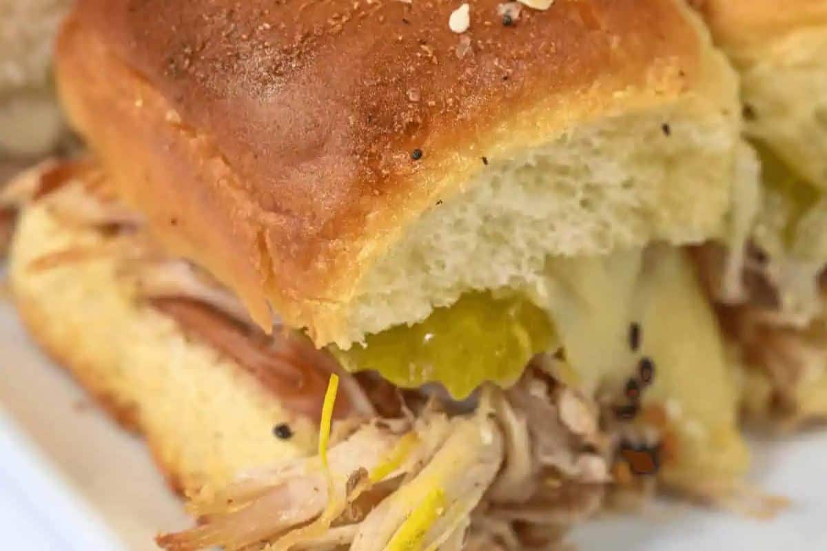 Irresistible close-up of a Cuban slider with pickles and melted cheese on a soft bread roll, perfect for Game Day feasting.