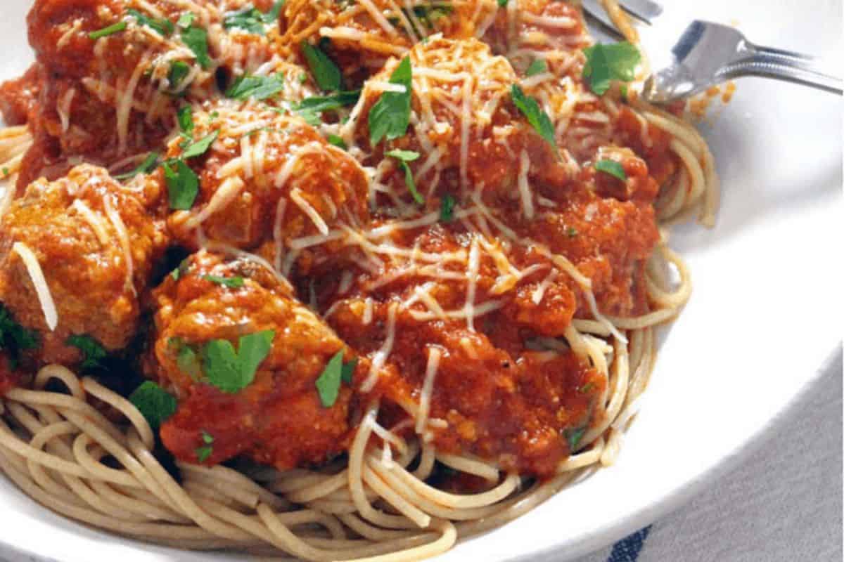 A plate of spaghetti topped with meatballs, marinara sauce, grated cheese, and fresh parsley, with a fork on the side—perfect for kid friendly dinner recipes the whole family will love.