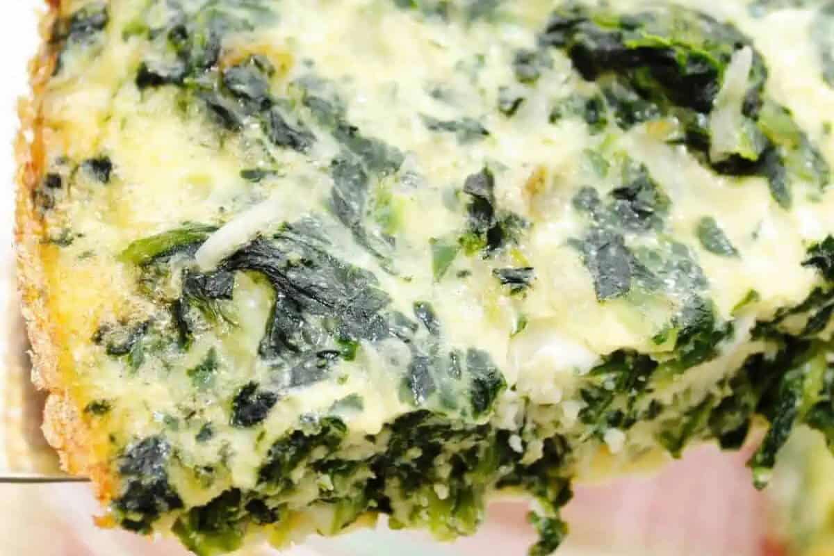 Close-up of a slice of baked spinach casserole with melted cheese on top—perfect for weekend brunch or lazy mornings.
