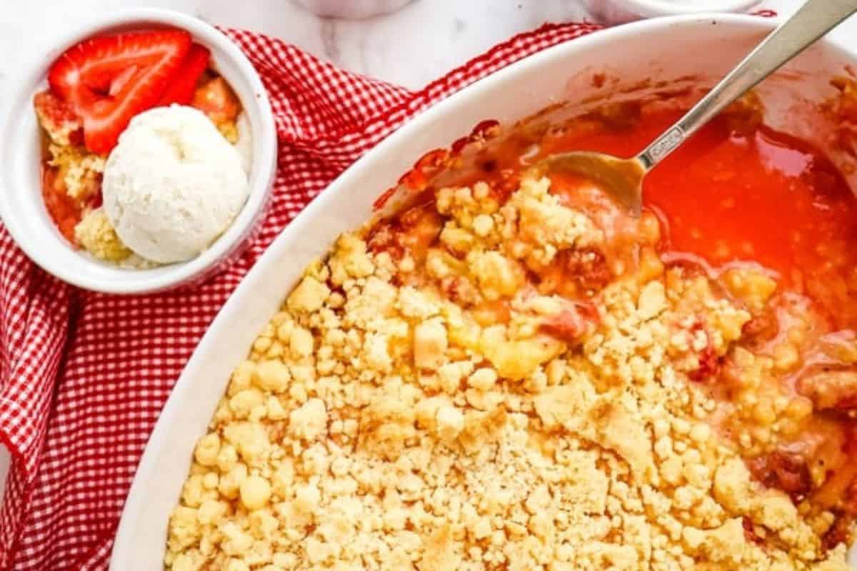 Close-up of a serving dish of strawberry dump cake, topped with a golden crumble. 