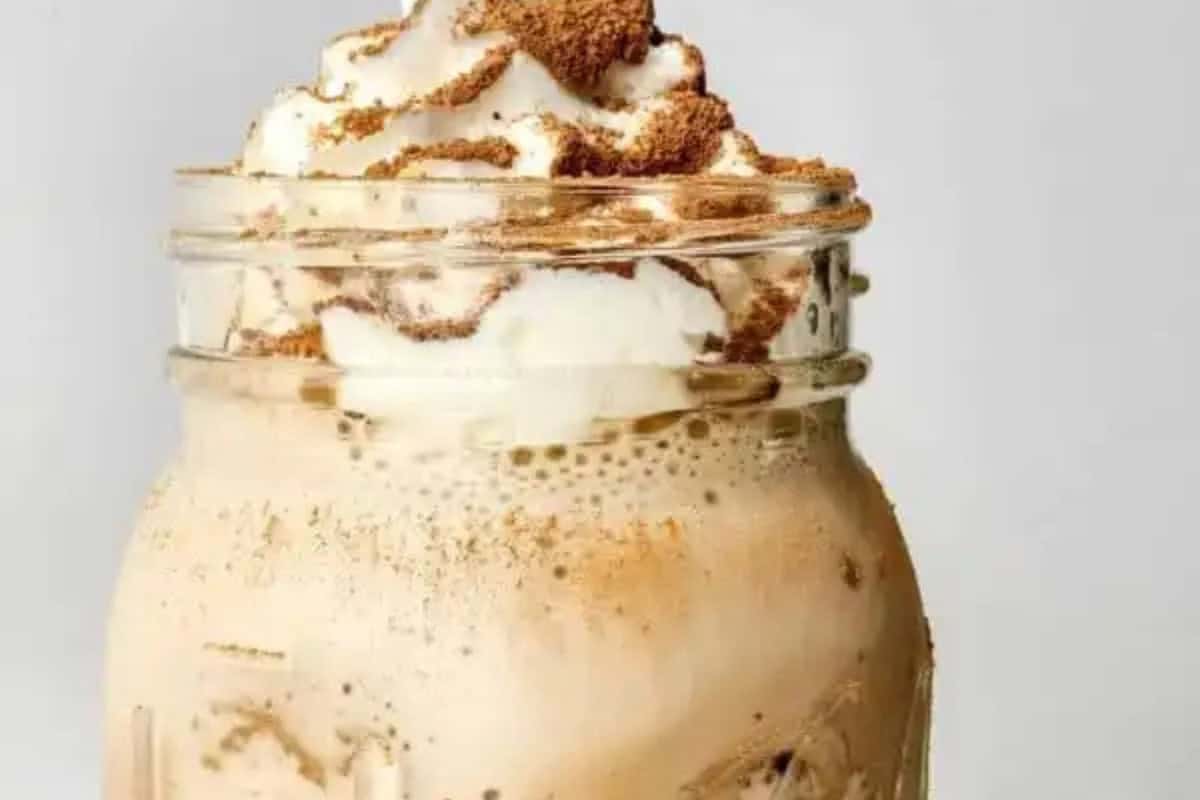 A mason jar filled with iced coffee, topped with whipped cream and sprinkled with cocoa powder—perfect to recreate at home if you love Starbucks drinks.