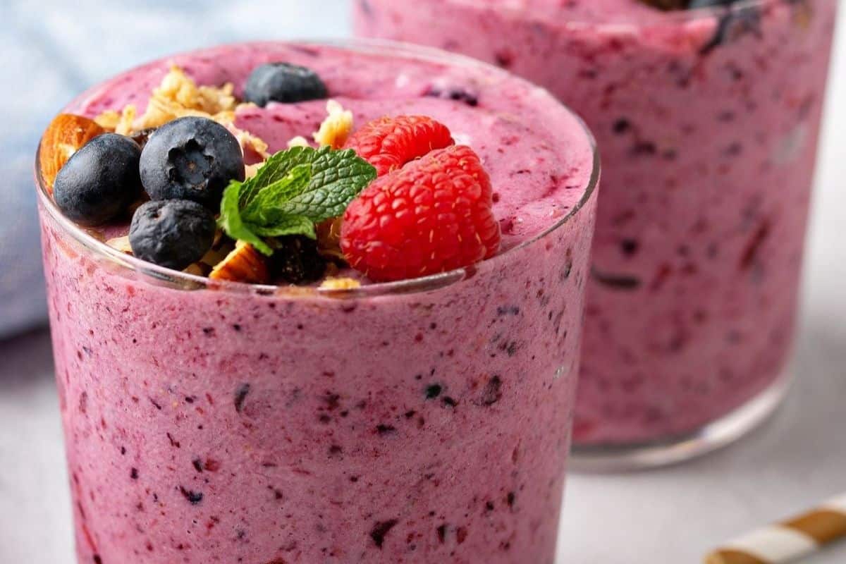 A triple berry smoothie topped off with blueberries, raspberries, and nuts. 