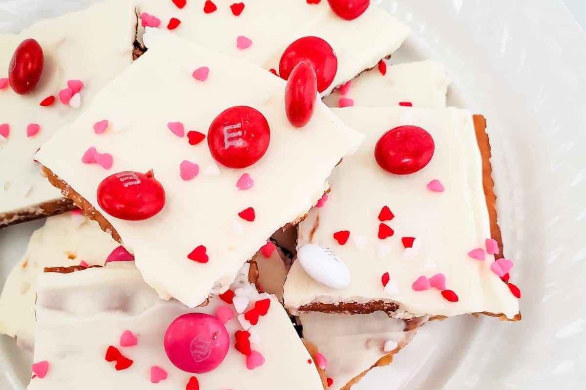 Square white chocolate treats with red and pink candy toppings rest on a white plate, perfect for inspiring Creative Valentine ideas. These delightful Little Sweethearts bring charm and sweetness to any occasion.