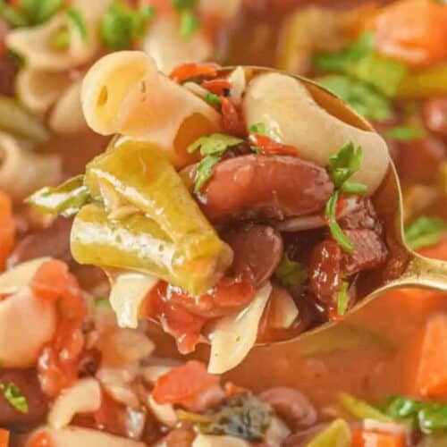 A spoonful of minestrone soup with pasta, green beans, kidney beans, carrots, tomatoes, and herbs—a classic pasta soup perfect for family friendly meals.