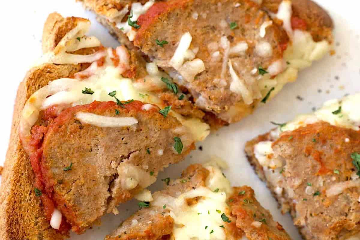 Slices of bread topped with tomato sauce, melted cheese, and meatloaf, garnished with chopped herbs—perfect for kid friendly dinner recipes that everyone will love.