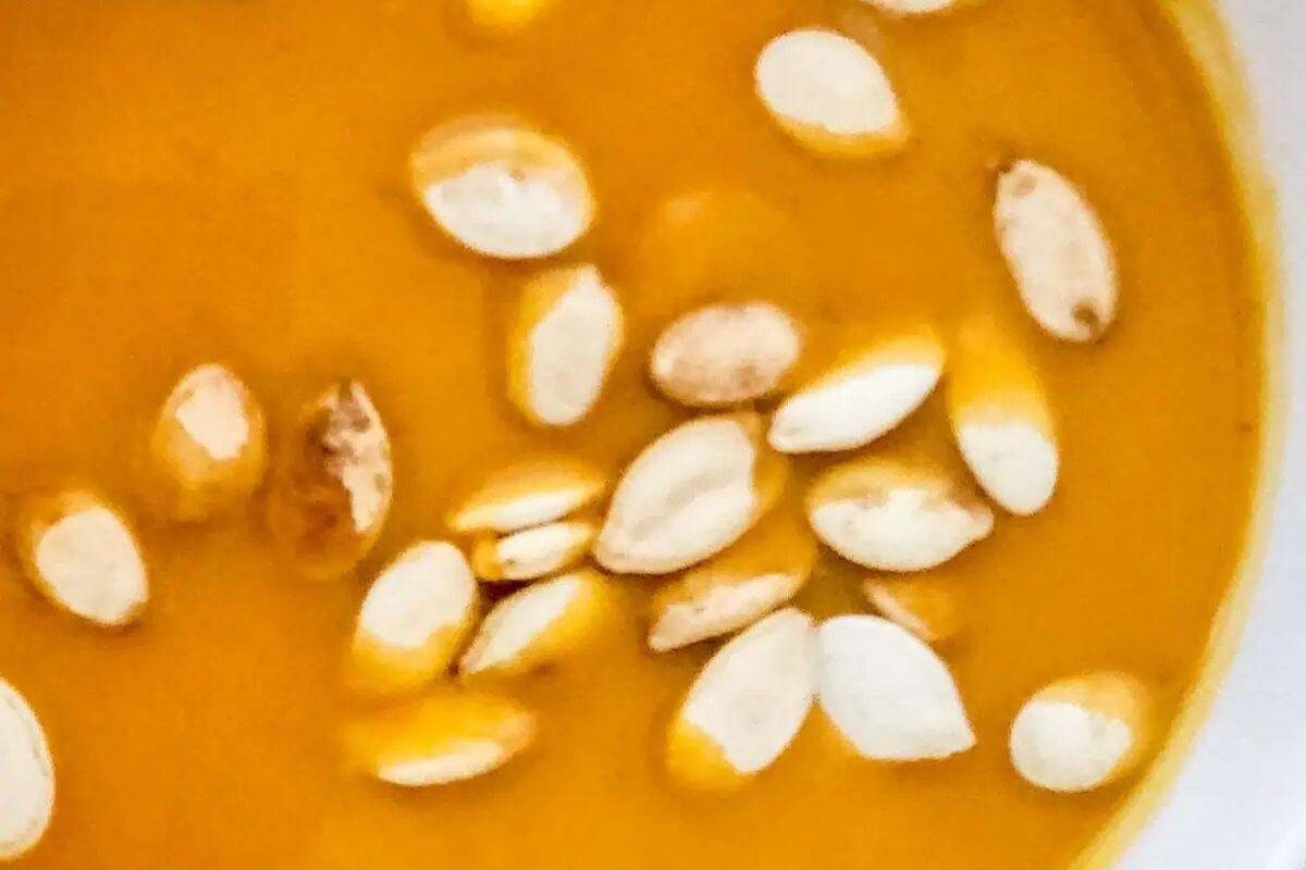 Close-up of autumn squash soup garnished with white pumpkin seeds, this cozy soup is perfect to warm up on chilly days.