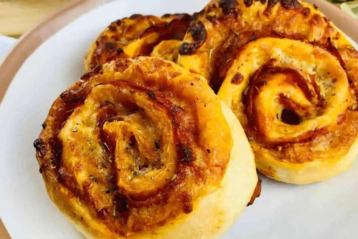 Three baked pizza rolls with a golden, crispy crust and visible layers of tomato sauce and cheese on a white plate—perfect for Kid Friendly Dinner Recipes.