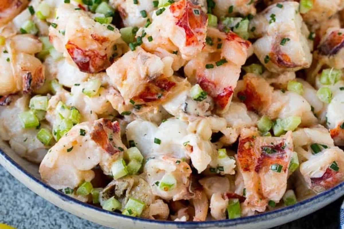 A close-up of lobster salad with diced lobster meat, chopped celery, mayonnaise, and garnished with chives in a bowl—perfect for cozy nights or as a highlight in your favorite Lobster recipes.