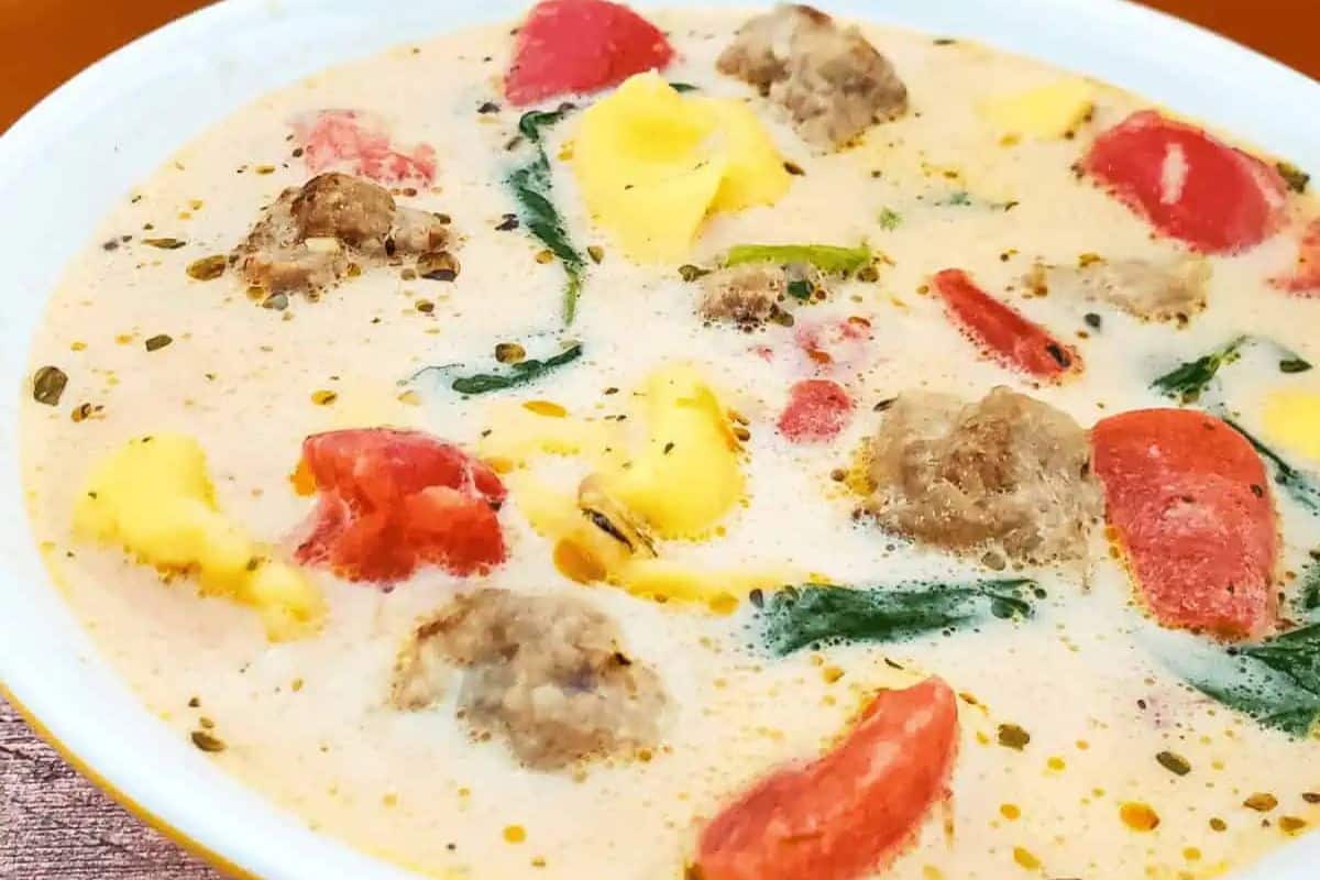 Bowl of creamy soup with meatballs, cheese tortellini, tomato pieces, and spinach in a white bowl—a delicious choice for fans of family friendly soups and classic pasta soups.