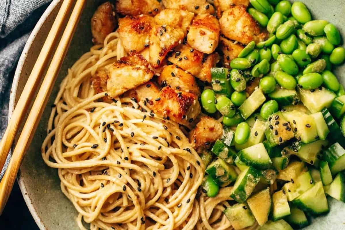 A bowl of noodles with grilled chicken, sliced cucumbers, edamame, and black sesame seeds, served with chopsticks—an ideal choice for those seeking Easy Weight Watchers Recipes.