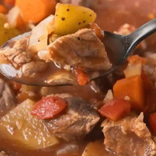 A close-up of a spoonful of beef stew with chunks of beef, potatoes, carrots, and tomatoes in broth—a family friendly favorite that everyone loves, perfect for anyone searching for delicious chuck roast recipes.