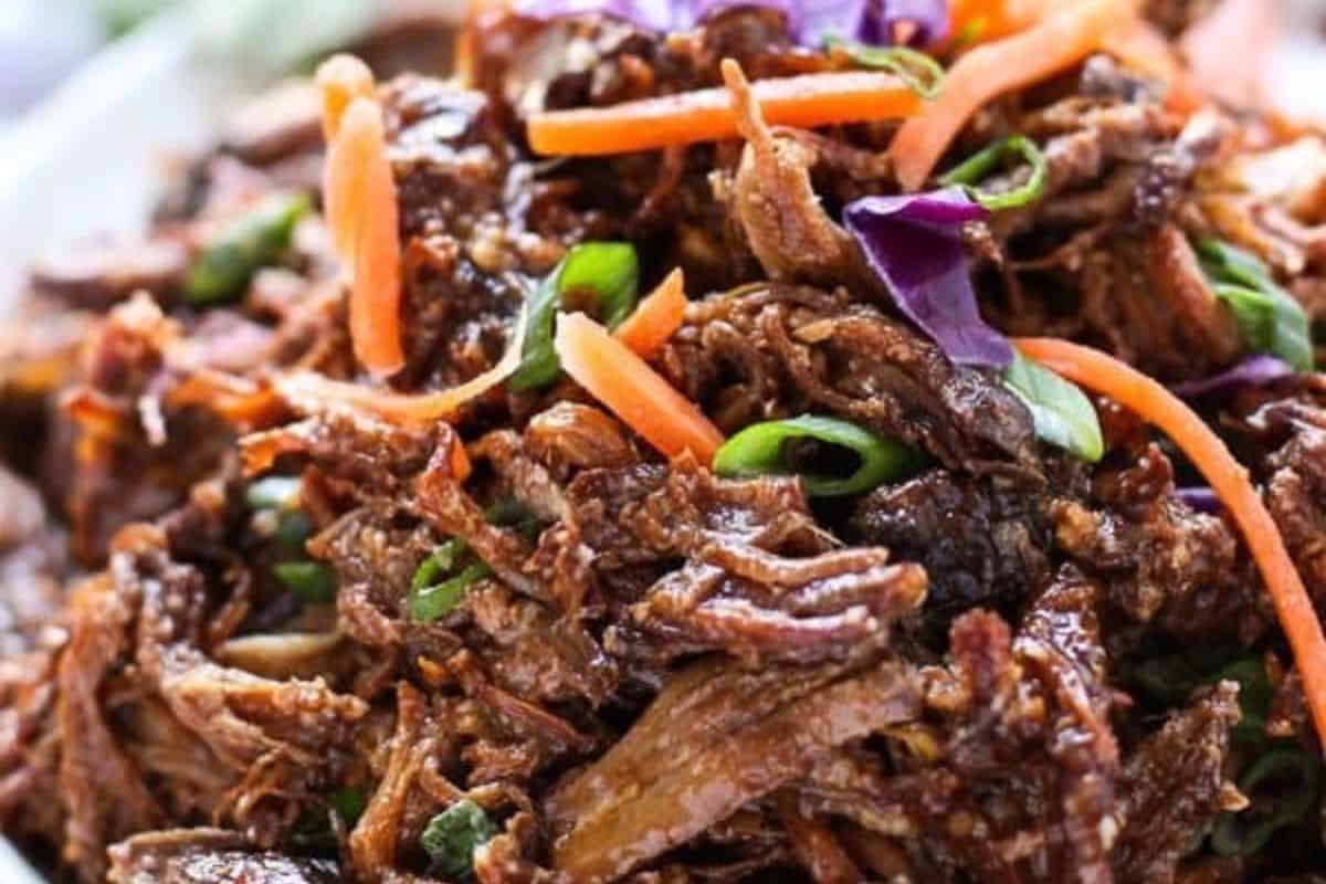 Close-up of shredded beef topped with sliced carrots, green onions, and purple cabbage—an easy dinner idea perfect for family friendly meals and delicious chuck roast recipes.