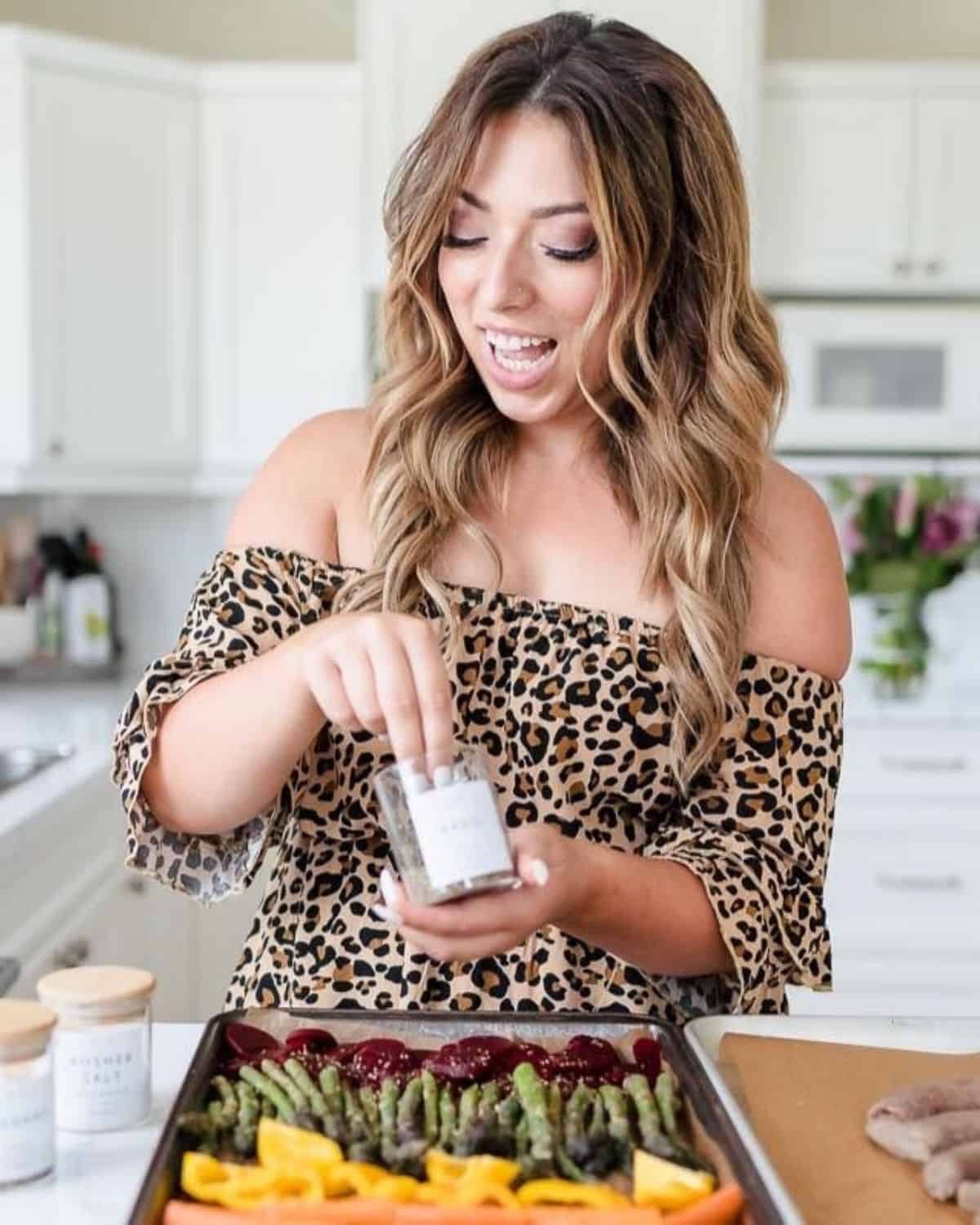 In a semi-homemade approach, a person in a leopard-print top uses smart shortcuts to season vegetables on a baking sheet, saving time in the kitchen.