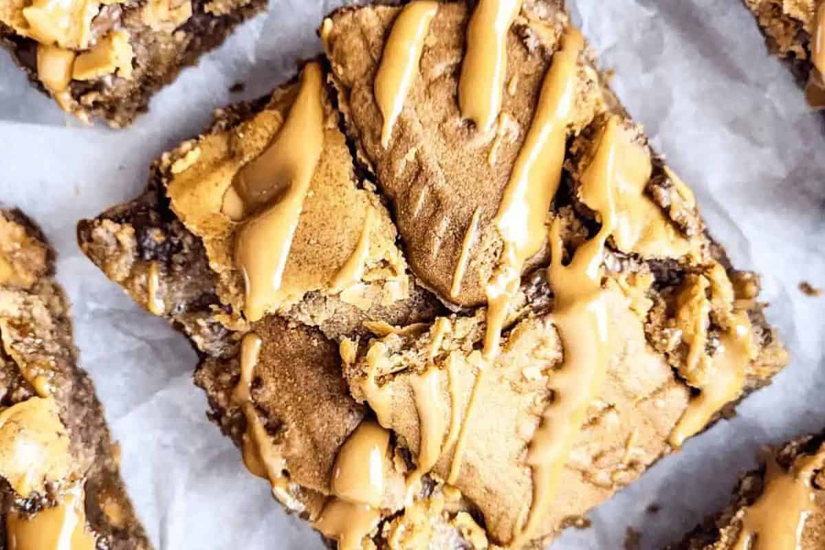 Close-up of a biscoff brownie topped with caramel drizzle, resting on parchment paper.