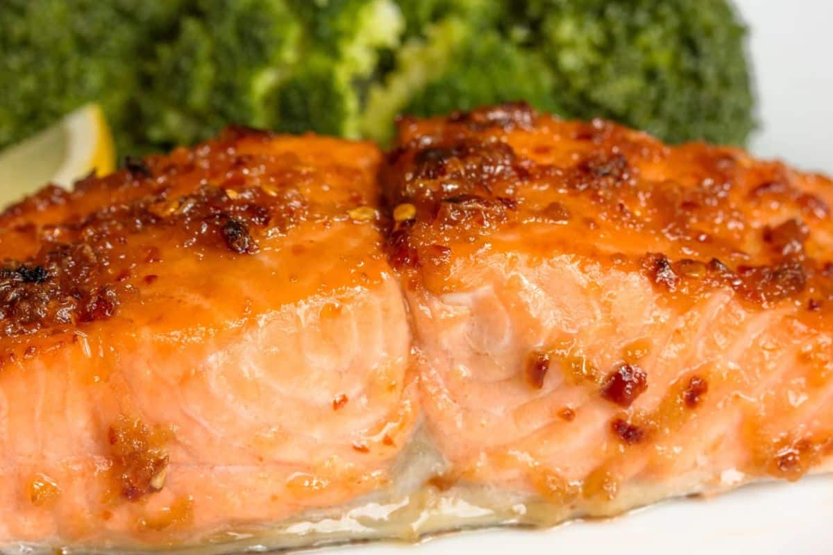 Irresistible salmon takes center stage in this close-up, featuring a perfectly cooked fillet with a luscious glaze. In the background, vibrant broccoli adds a touch of color to a dish everyone will love.